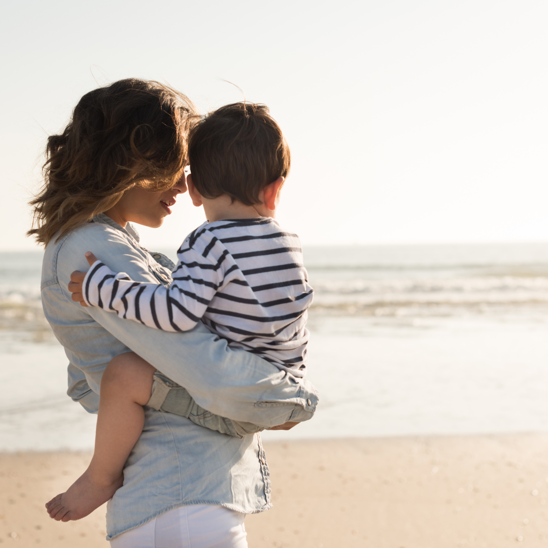 Mutter und Sohn kuscheln am Strand