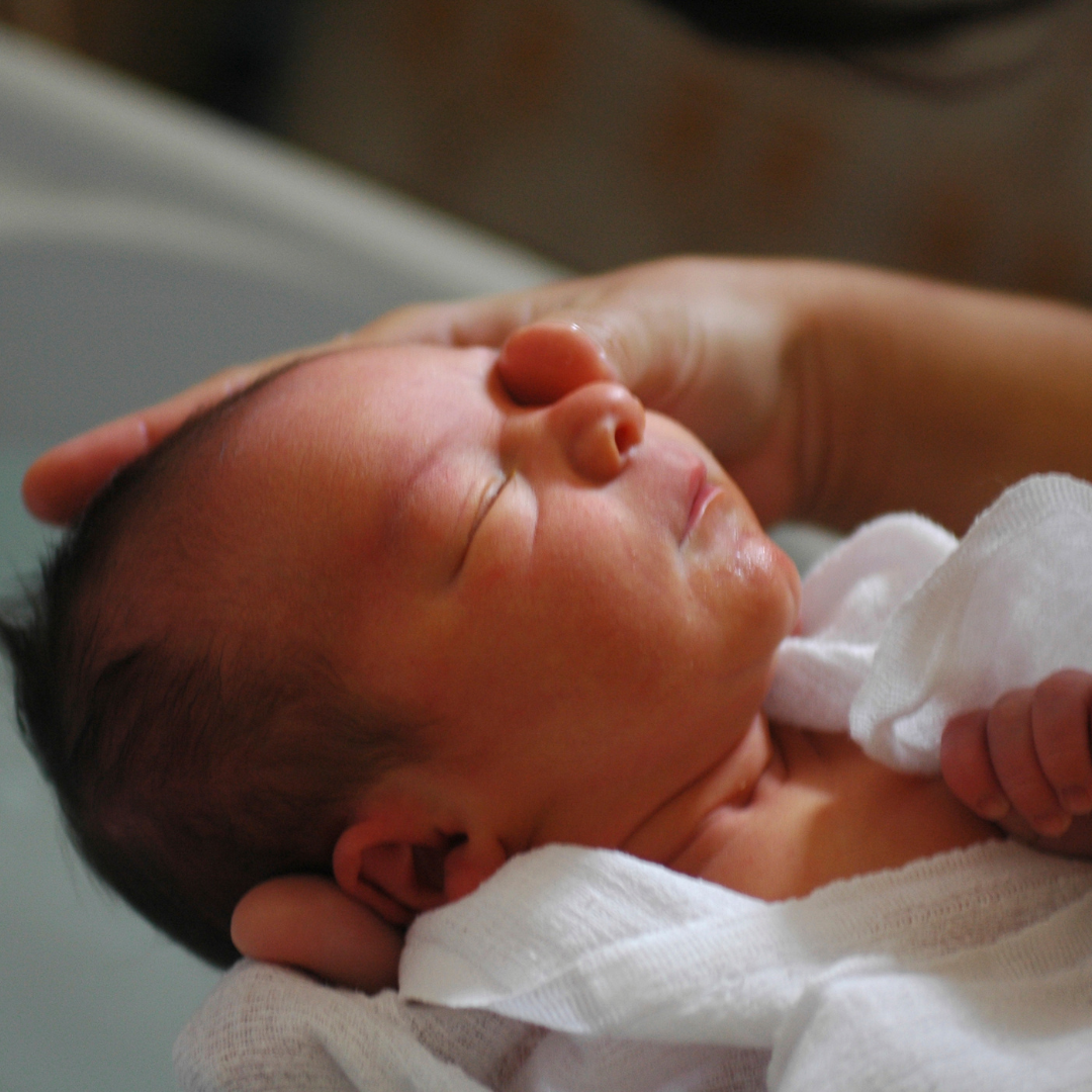 Zufriedenes Baby, das von seinen Eltern gebadet wird